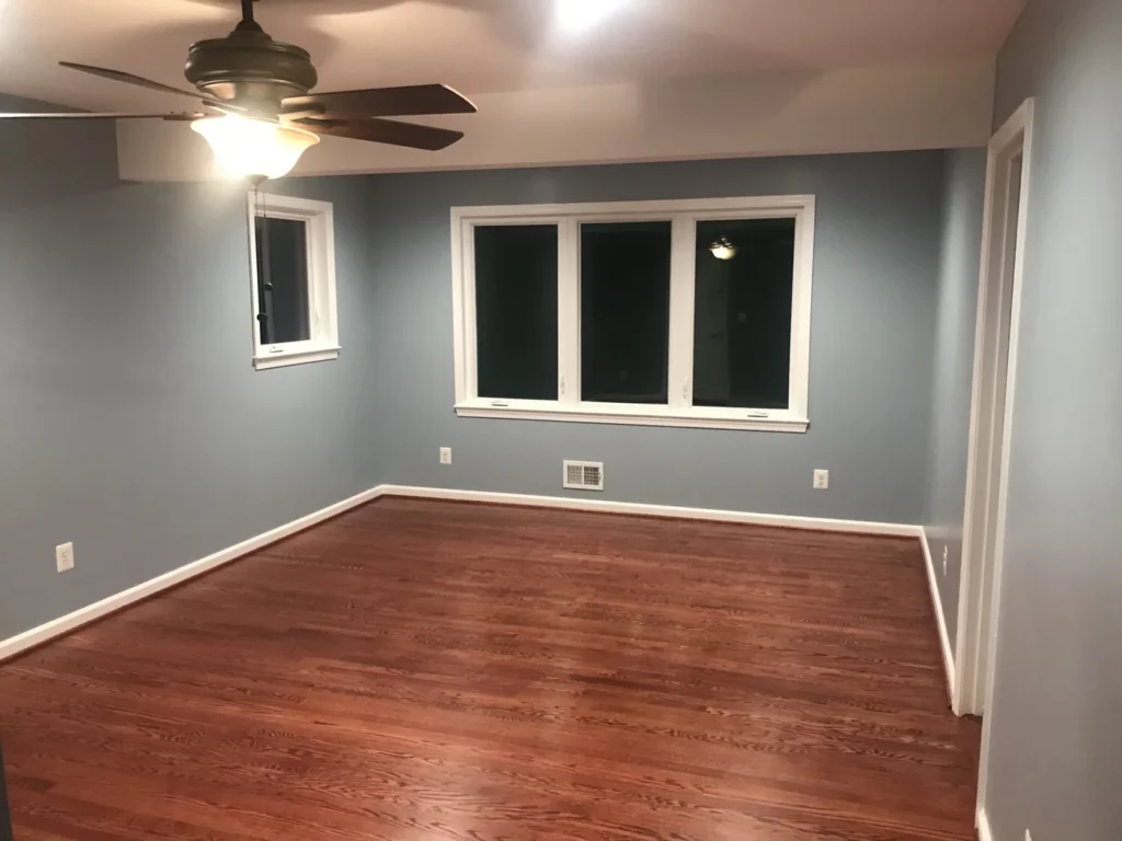 New bedroom with blue walls, hardwood floor and a ceiling fan