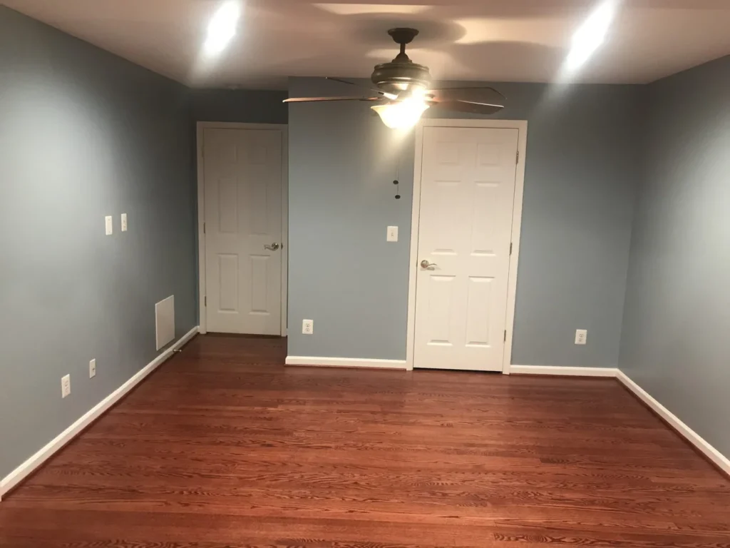 Blue bedroom with paneled doors and stained hardwood floor