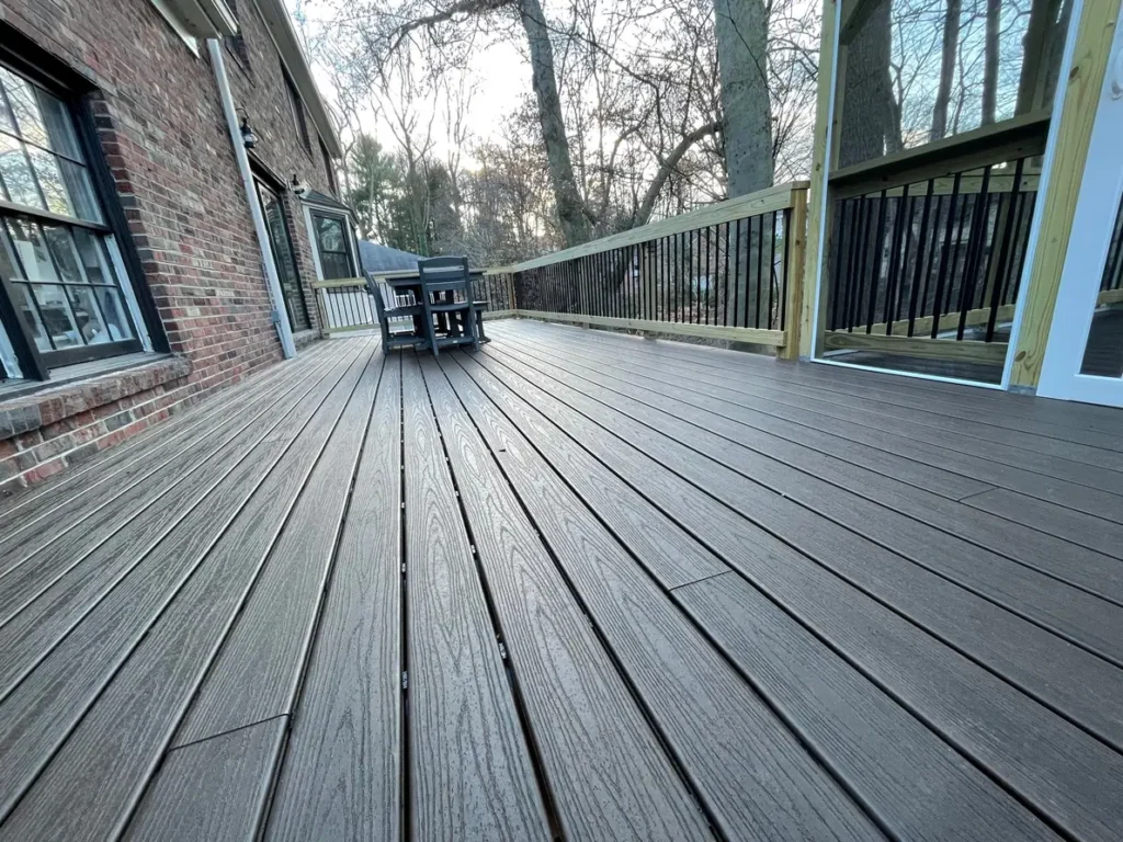 Long composite deck with black metal balusters along a brick home