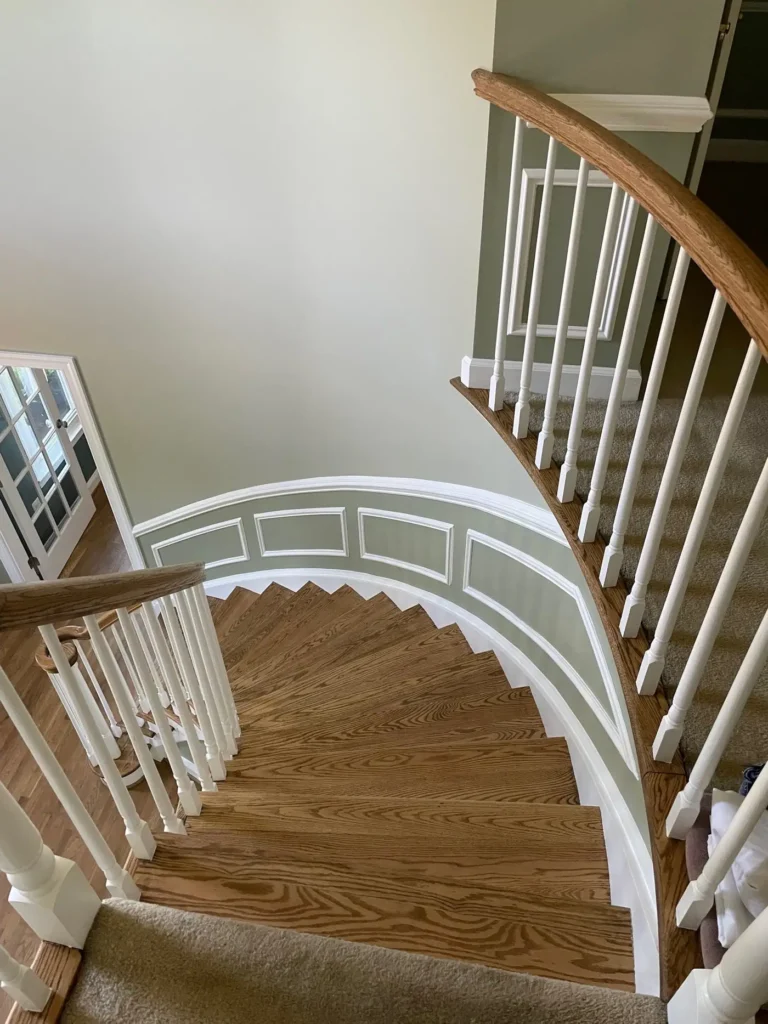 Curved staircase with a stained wood handrail and white balusters