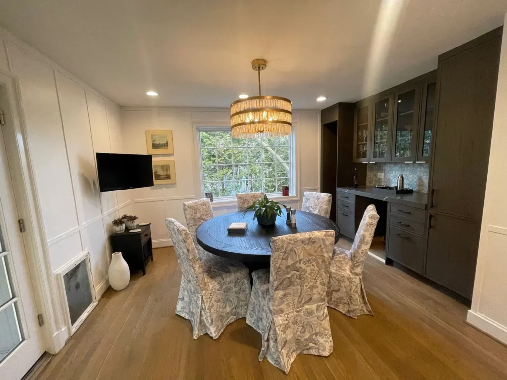 Dining area with a round table, a drum chandelier and dark built-in cabinets