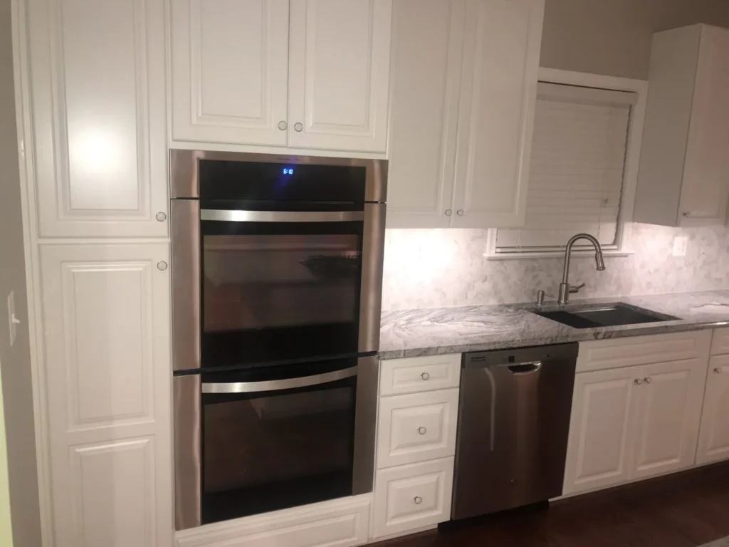 Double wall ovens in white cabinetry with granite counters