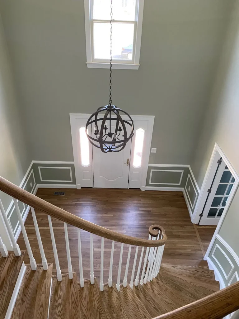 Whole house remodeling project: two-story foyer with a curved staircase, wainscoting and an orb chandelier
