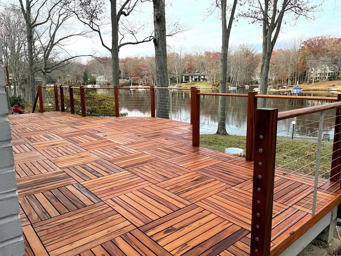 Hardwood deck with parquet-pattern boards and cable railing overlooking a lake