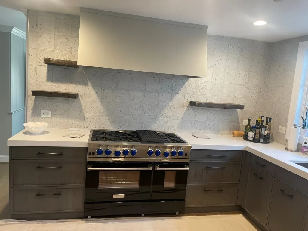 Kitchen with dark gray lower cabinets, a six-burner range and a plaster range hood
