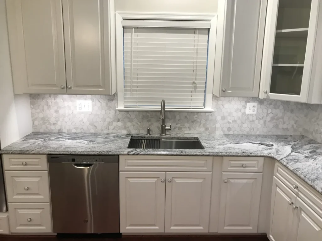 White kitchen cabinets with granite counters and a sink under the window