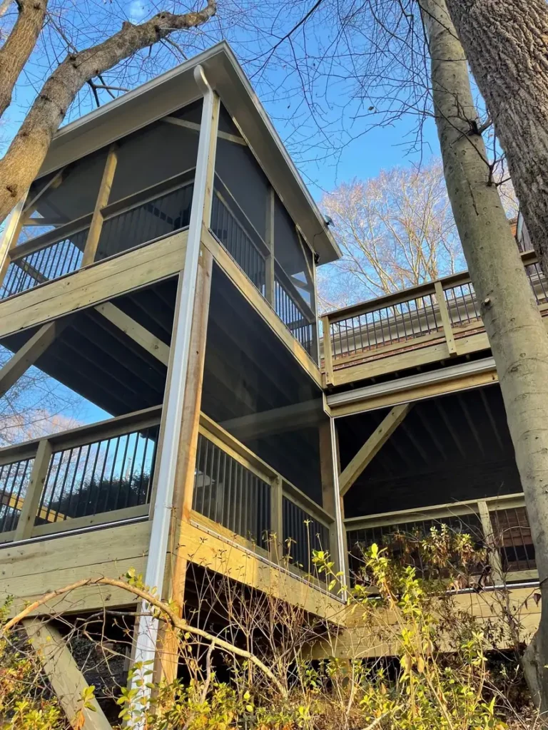 Multi-level screened porch and deck seen from below among tall trees