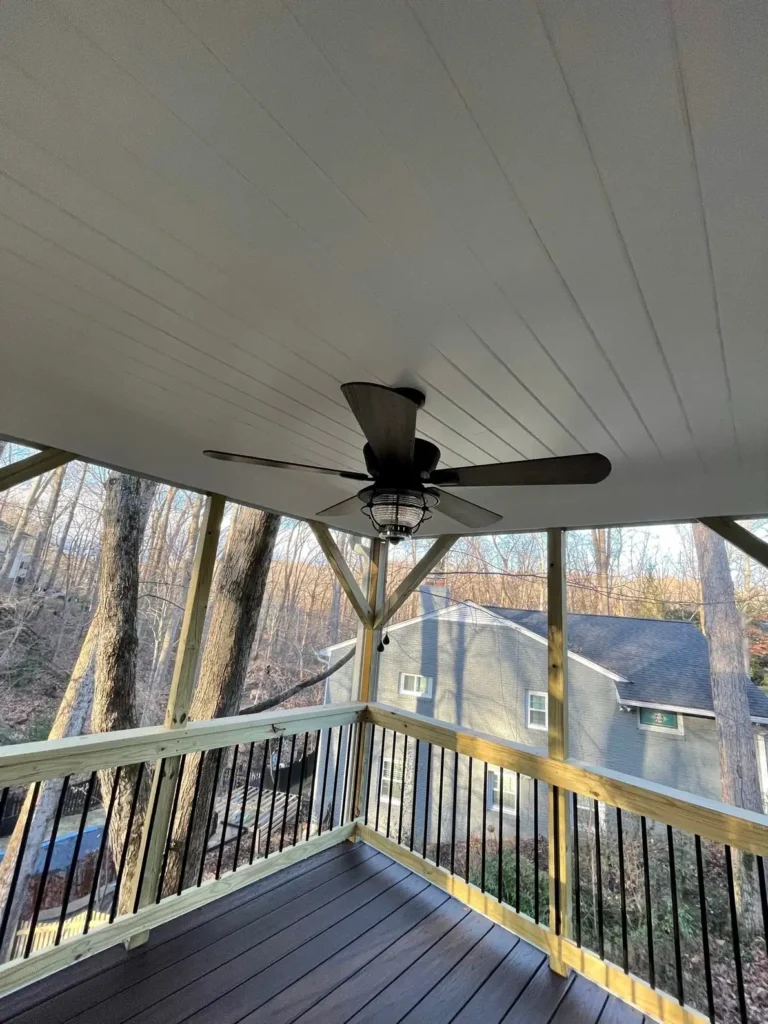 White beadboard porch ceiling with a ceiling fan above black railings