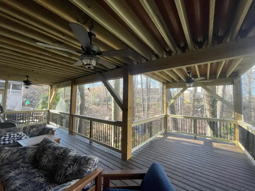 Furnished screened porch with exposed joists, ceiling fans and a composite floor