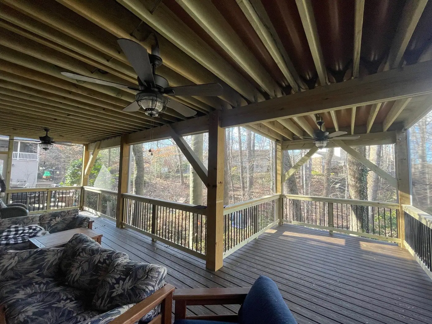 Furnished screened porch with exposed joists, ceiling fans and a composite floor
