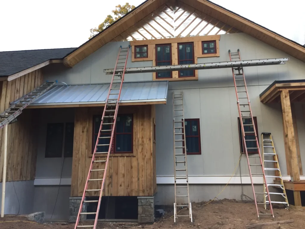 Second-story addition under construction with cedar accents and ladders on the siding
