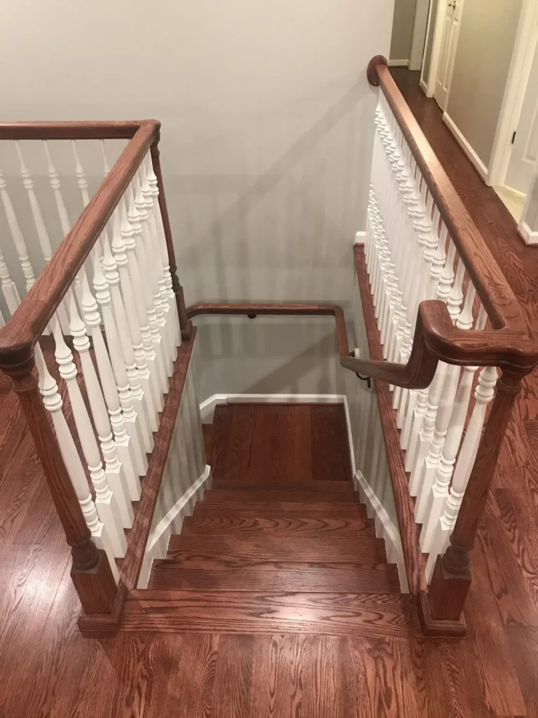 Stairwell with a stained handrail and white balusters over hardwood steps
