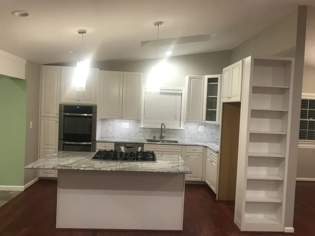 White kitchen with a granite island cooktop and built-in shelving