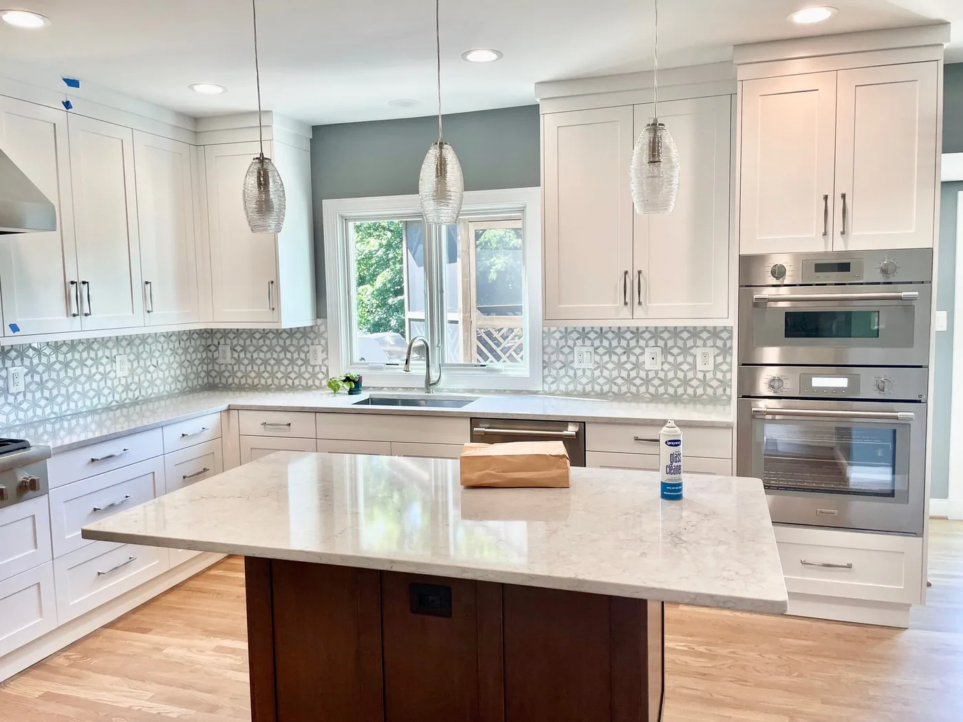 Kitchen remodeling project: white kitchen with a wood island, quartz top, glass pendants and a patterned backsplash