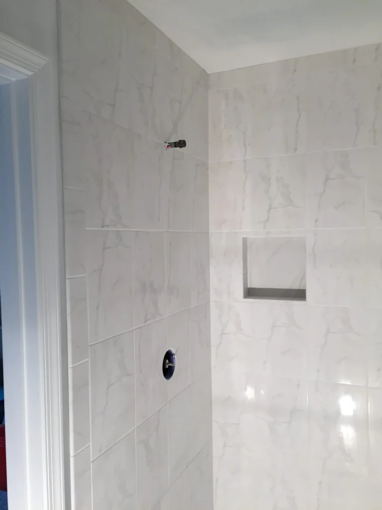 Shower wall in large white tile with a recessed niche